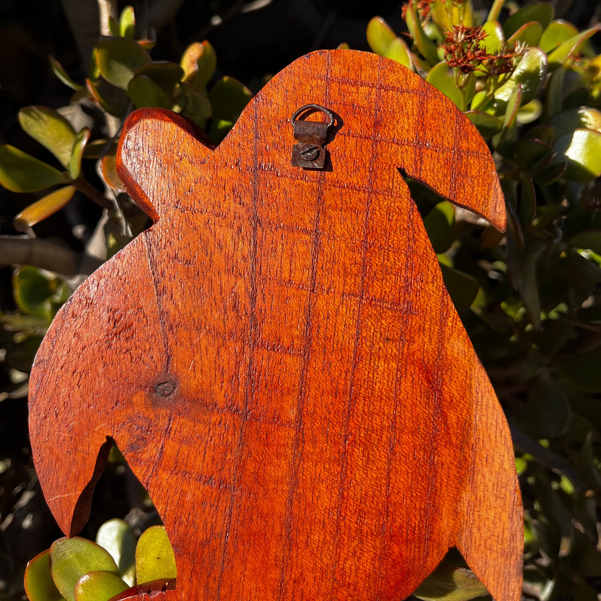 Detailed close-up of the hook on the back of a hand-carved wooden turtle wall plaque featuring three turtles. Shows the secure mounting design for easy hanging.