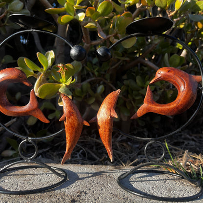 Handmade dolphin candle holder, carved from wood, featuring an elegant design, displayed on a nature-themed background. 