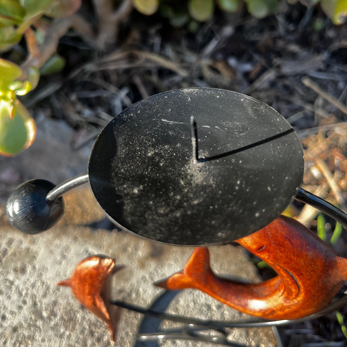Handcrafted dolphin candle holder with candle stick display, featuring a unique design, shown against a nature-inspired background. 